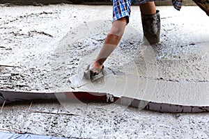 Construction worker spreading concrete during flooring