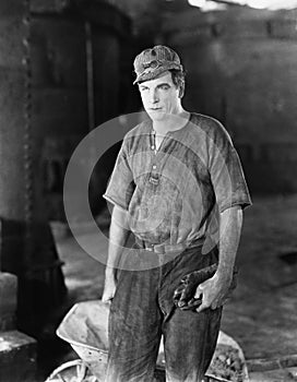 Construction worker standing near a wheelbarrow