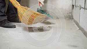 Construction worker sweeping dust with broom and dustpan