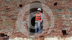 Construction worker take pictures on smarth phone near old wall