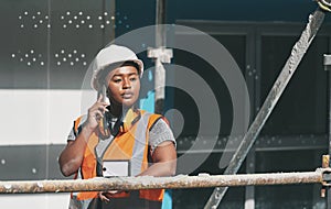 Construction worker talking on a phone call while standing in a building site. Professional builder discussing plans and