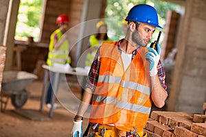 Construction worker talking on walkie talkie at site photo
