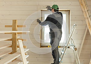 Construction worker thermally insulating eco wooden frame house.