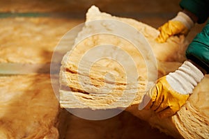 Construction worker thermally insulating house attic with glass wool.