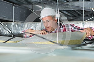 Construction worker thermally insulating house attic with mineral wool