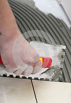 Construction worker is tiling at home, tile floor adhesive