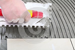 Construction worker is tiling at home, tile floor adhesive