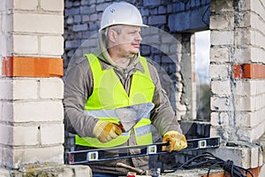 Construction worker with trowel and level near wall