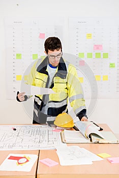 Construction Worker Turning Pages While Holding Blueprint