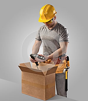 Construction worker unpacks the box with delivery drill