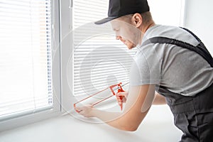 Construction worker use gun silicone tube for repairing and installing window in house