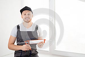 Construction worker use gun silicone tube for repairing and installing window in house
