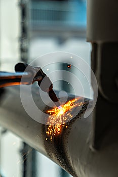 Construction worker using blowtorch welding metal pipe on construction site