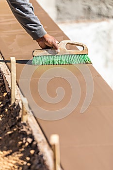 Construction Worker Using Brush On Wet Cement Forming Coping Around New Pool