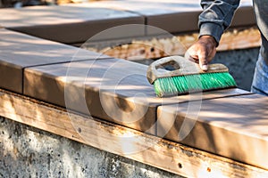 Construction Worker Using Brush On Wet Cement Forming Coping Around New Pool