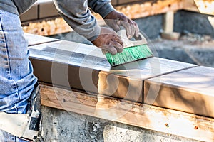 Construction Worker Using Brush On Wet Cement Forming Coping Around New Pool