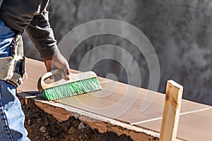 Construction Worker Using Brush On Wet Cement Forming Coping Around New Pool