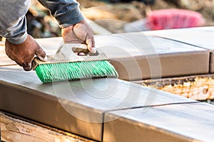 Construction Worker Using Brush On Wet Cement Forming Coping Around New Pool