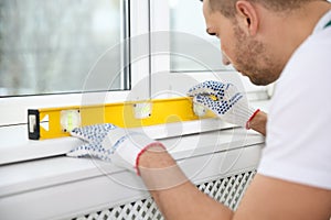 Construction worker using bubble level while installing window