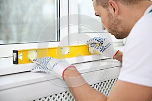 Construction worker using bubble level while installing window
