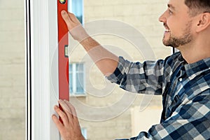 Construction worker using bubble level while installing window indoors