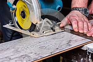 Construction worker using circular saw to cutting laminate for installation.