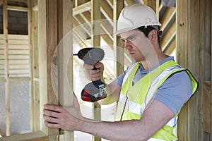 Construction Worker Using Cordless Drill On House Build