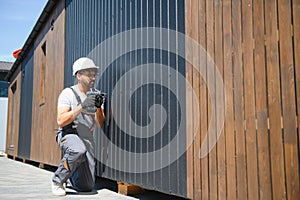 Construction worker using cordless drill installing modular house panel