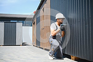 Construction worker using cordless drill installing modular house panel