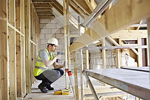 Construction Worker Using Drill On House Build