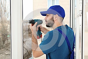 Construction worker using drill while installing window