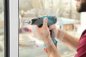 Construction worker using drill while installing window indoors