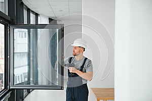 Construction worker using drill while installing window indoors