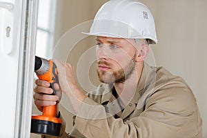 construction worker using drill to install replacement window