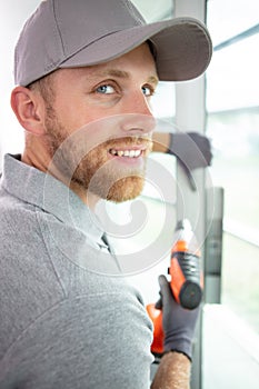 construction worker using drill to install window