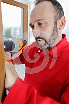 construction worker using drill to install window