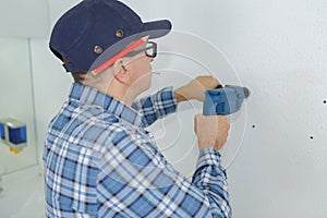 Construction worker using electric drill on building site
