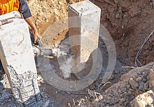 Construction worker using electric jackhammer drill to break reinforced concrete pillar