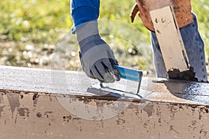 Construction Worker Using Hand Groover On Wet Cement Forming Coping Around New Pool