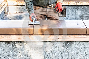 Construction Worker Using Hand Groover On Wet Cement Forming Coping Around New Pool