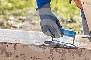 Construction Worker Using Hand Groover On Wet Cement Forming Coping Around New Pool