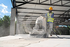 A Construction worker using machine polishing surface floor smoothing and finishing hardener or epoxy concrete at construction