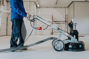 Construction worker using machine polishing surface floor smoothing and finishing hardener or epoxy concrete in the factory