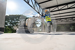 Construction worker using machine polishing surface floor smoothing and finishing hardener or epoxy concrete at construction site