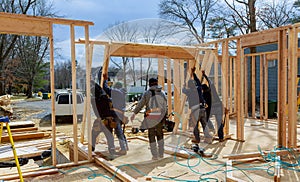 Construction Worker Using nail gun On wood building frame against