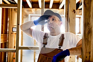 Construction Worker Using Power Tool in Unfinished Basement of New Home