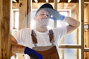 Construction Worker Using Power Tool in Unfinished Basement of New Home