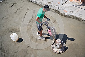 Construction worker using power trowel machine outdoors.