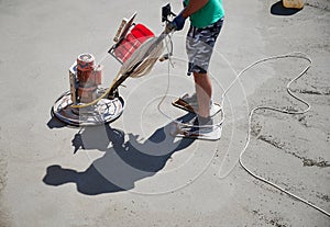 Construction worker using power trowel machine outdoors.