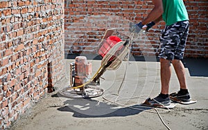 Construction worker using power trowel machine outdoors.